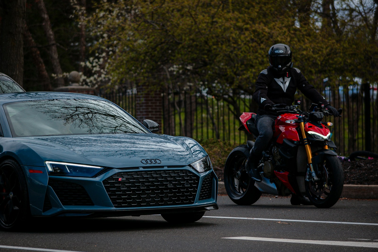 a man riding a motorcycle next to a blue sports car, auto & motorcycle